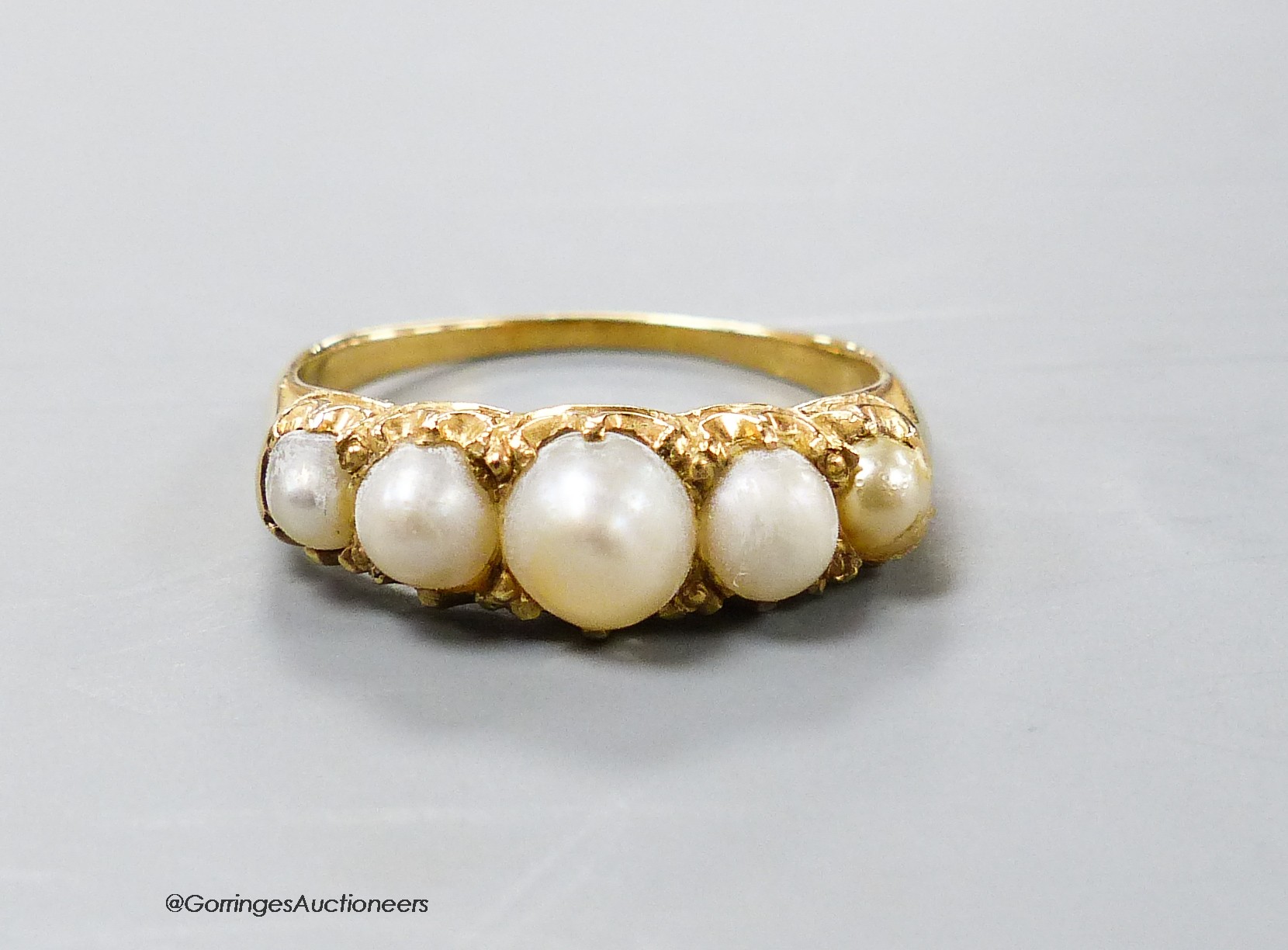 A yellow metal and graduated five stone split pearl half hoop ring, size R, gross weight 3.8 grams.